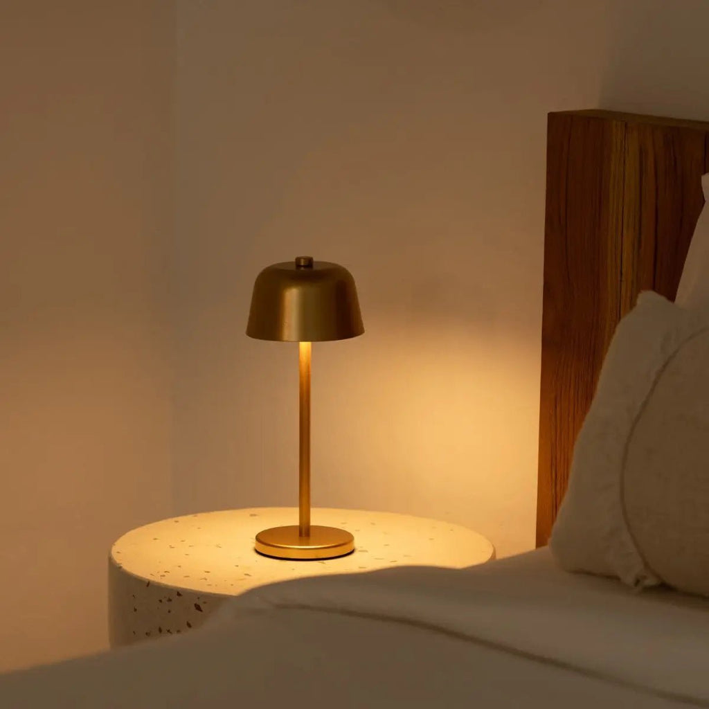 Lampe d'ambiance dorée diffusant une lumière chaude et douce dans un coin de lit