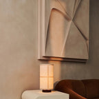 Lampe à poser Japandi diffusant une lumière douce, avec son abat-jour en lin texturé et son socle en bois.