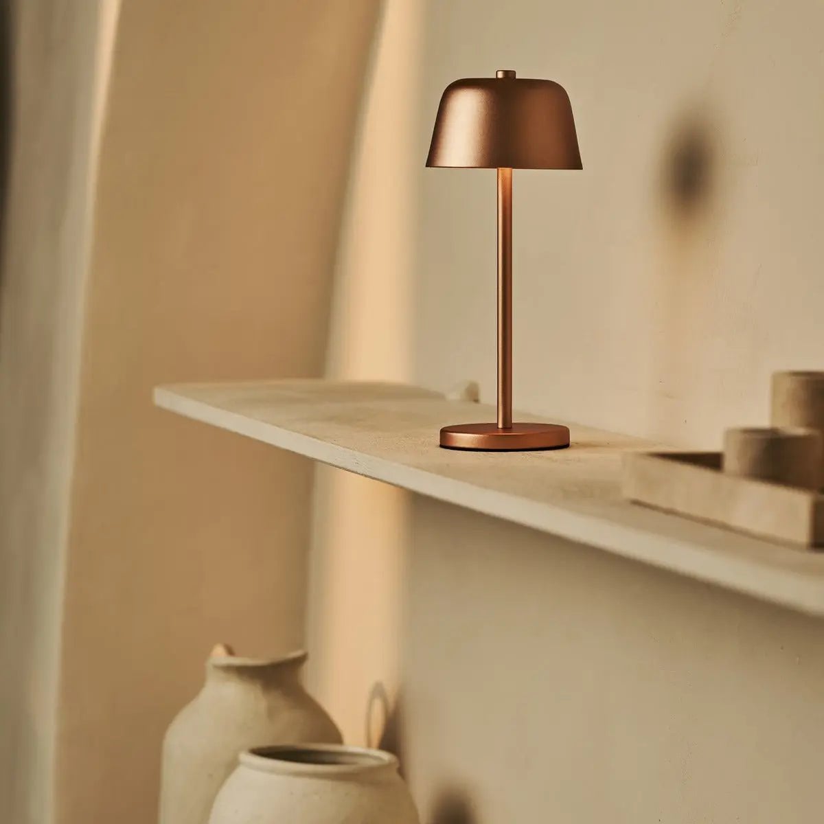 Lampe sans fil couleur cuivre Anton sur une étagère minimaliste beige.