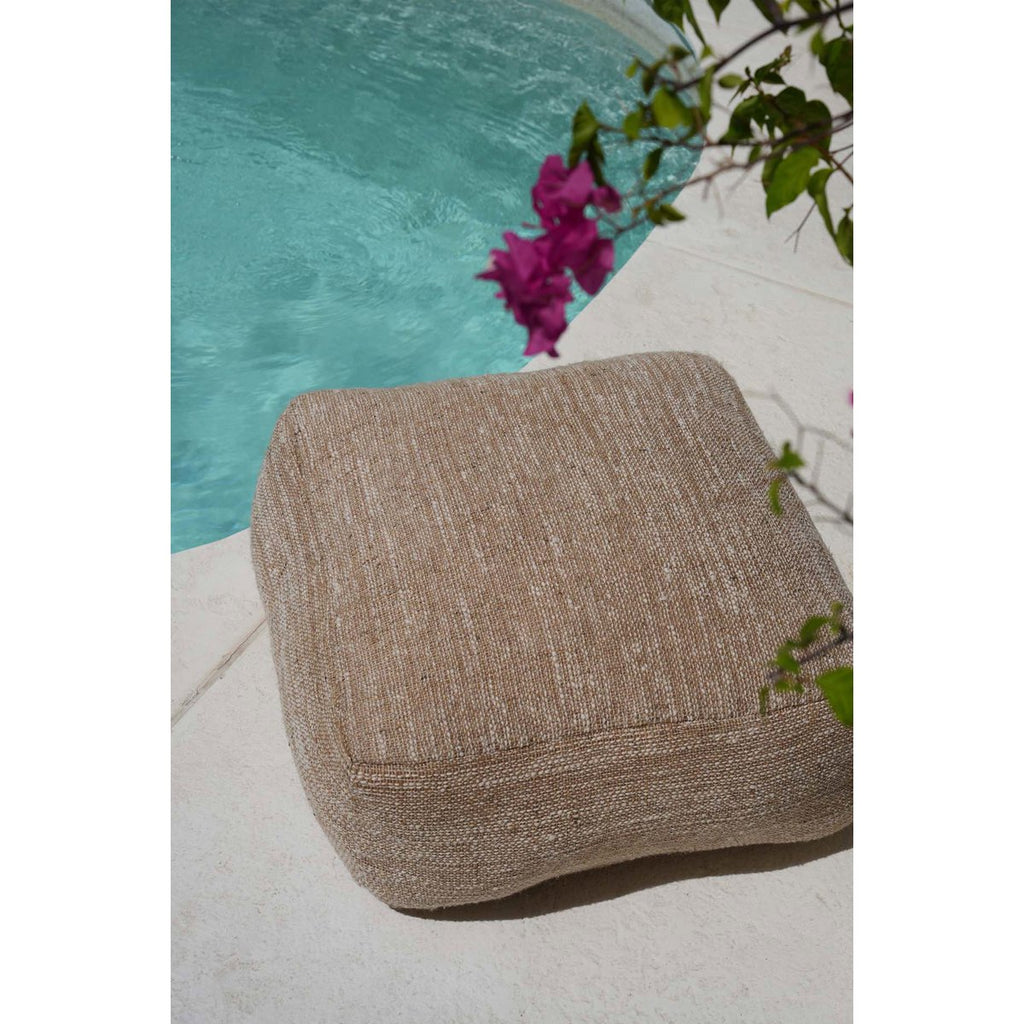 Mise en scène du pouf beige clair utilisé comme assise relaxante en extérieur sur une terrasse.