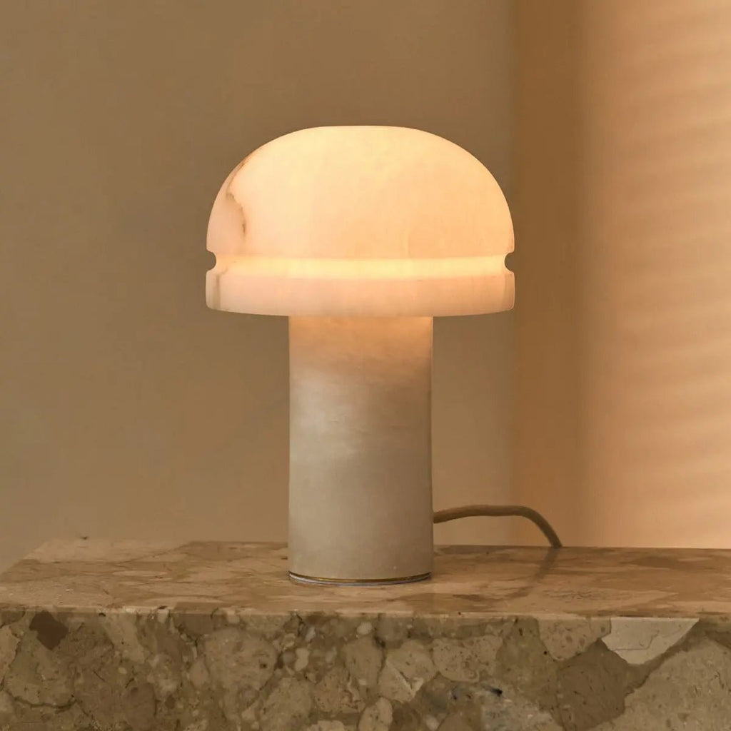 Lampe à poser Leonardo en albâtre allumée, pierre translucide diffusant une lumière chaude.