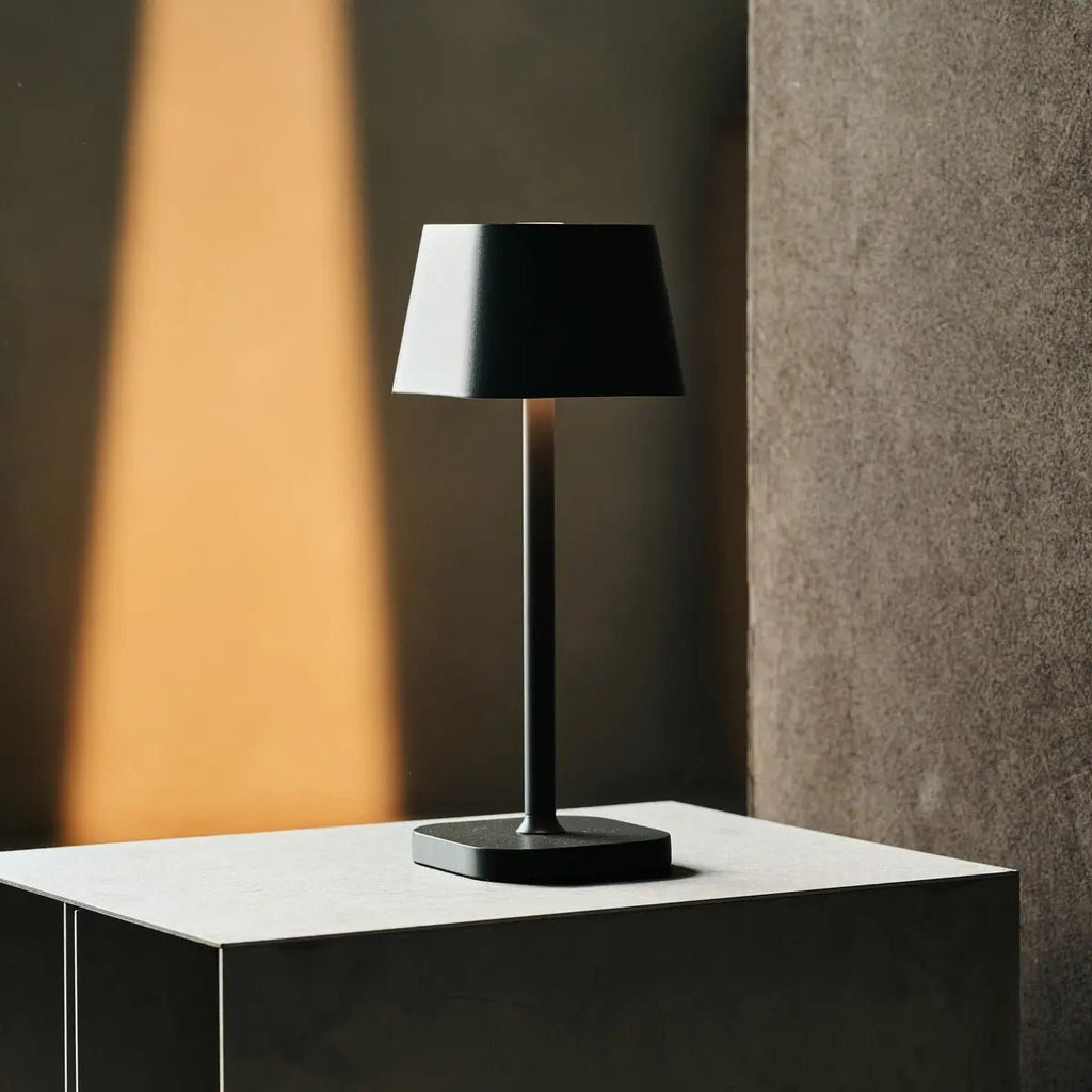 Lampe sans fil design Tavellio Ava Stone Grey sur un socle noir éclairage d'ambiance.