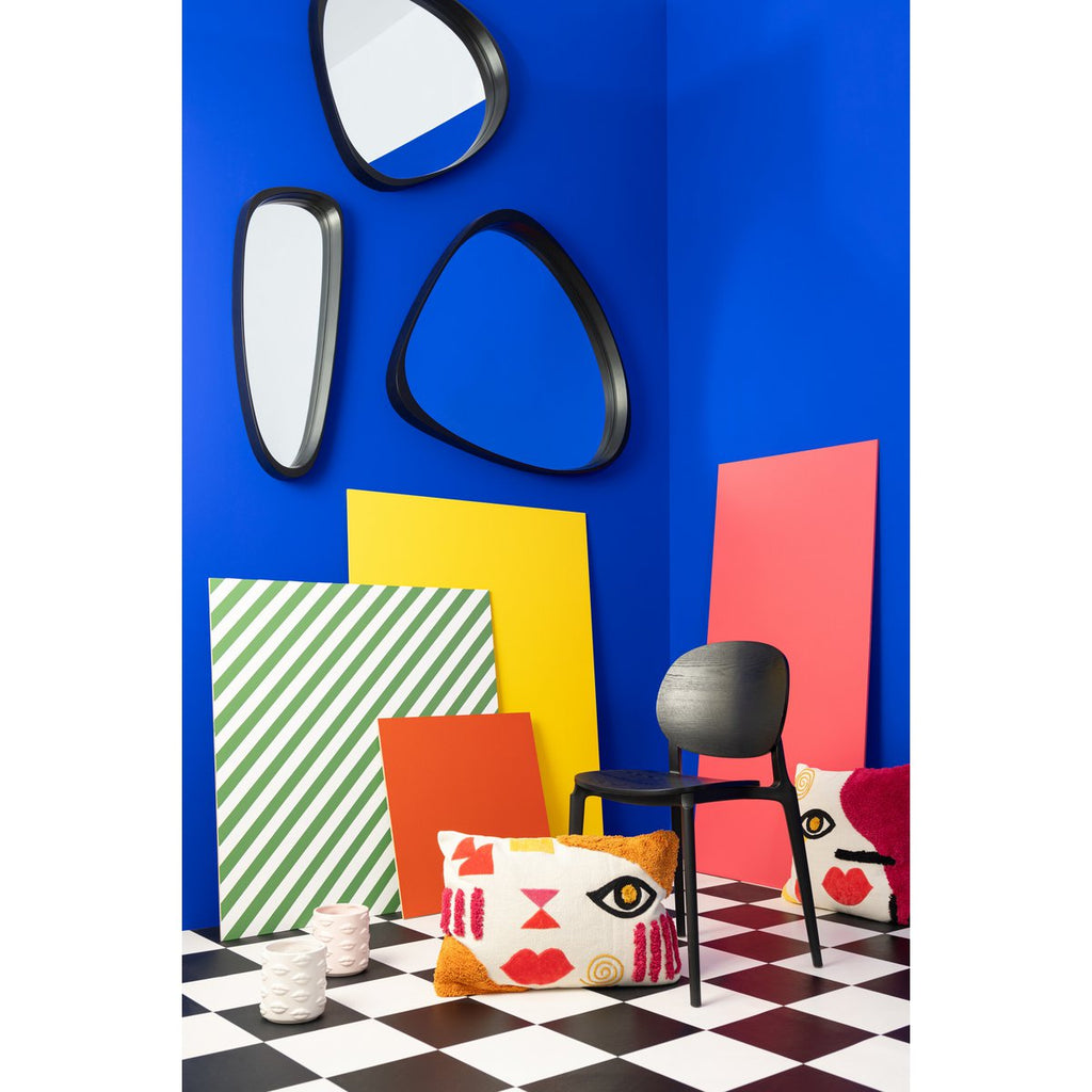 Mise en scène très colorée et arty montrant le miroir noir organique posé sur une console.