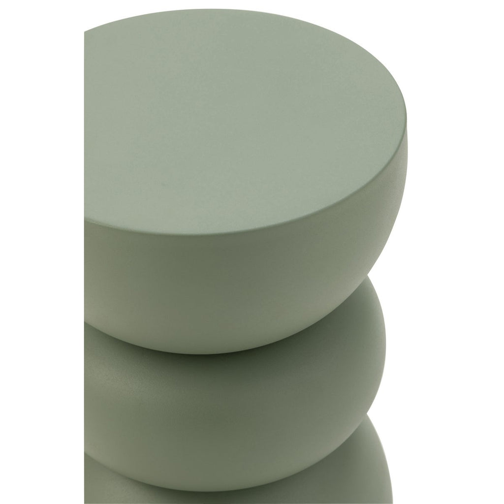 Table d'appoint design en métal vert sauge mat, avec une forme sculpturale rappelant des galets empilés.