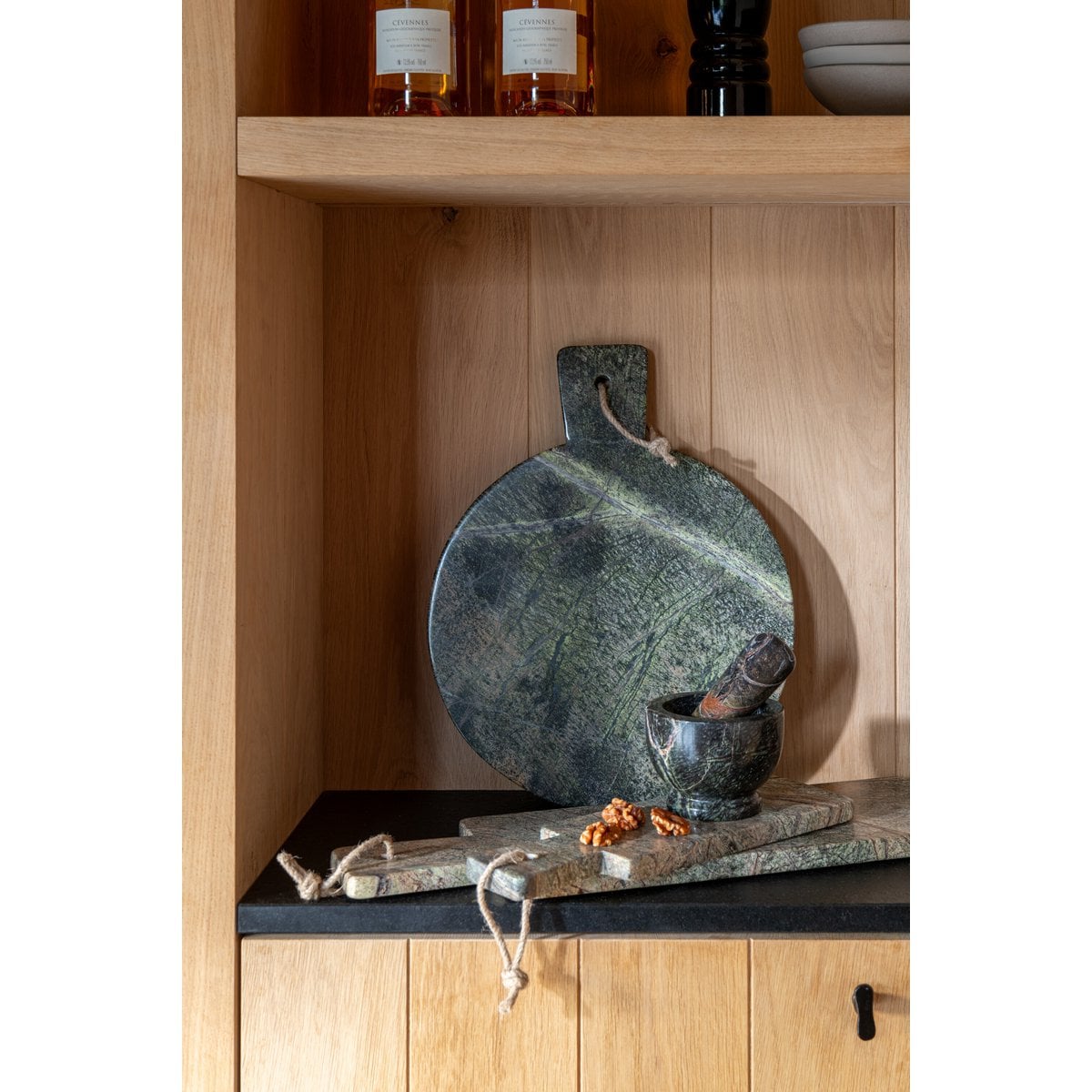 Mise en scène de la planche en marbre vert posée sur une étagère de cuisine en bois.