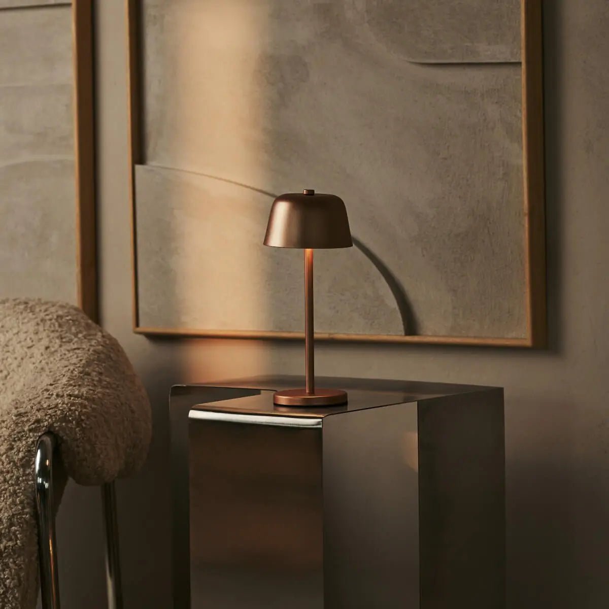 Lampe nomade cuivre Anton posée sur une console sombre, reflets élégants.