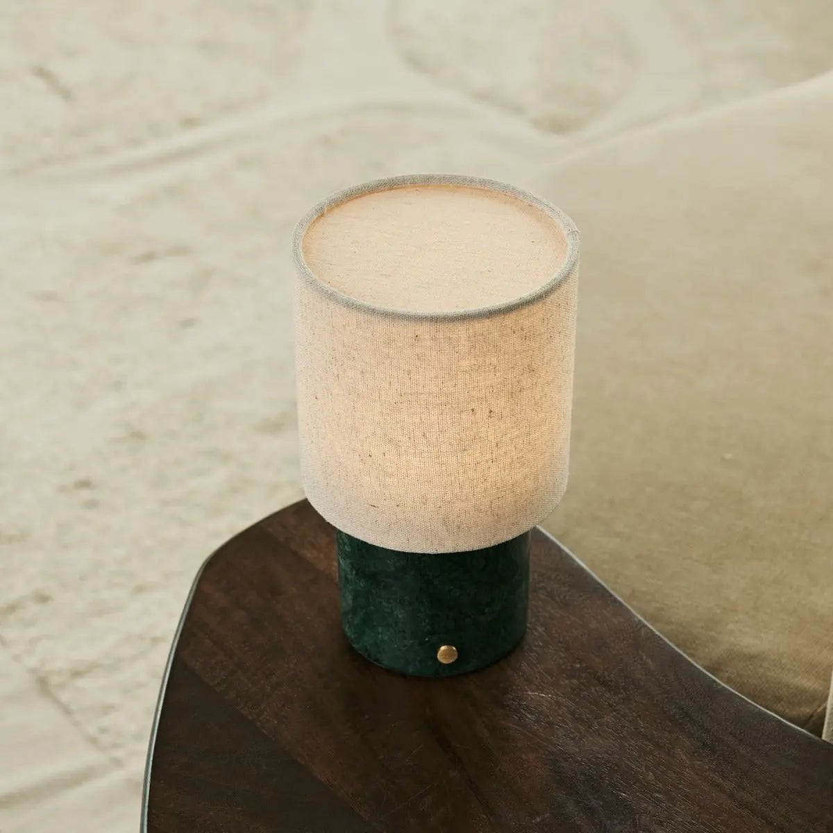 Lampe rechargeable Onoda posée sur le coin d'une table en bois foncé texturé.