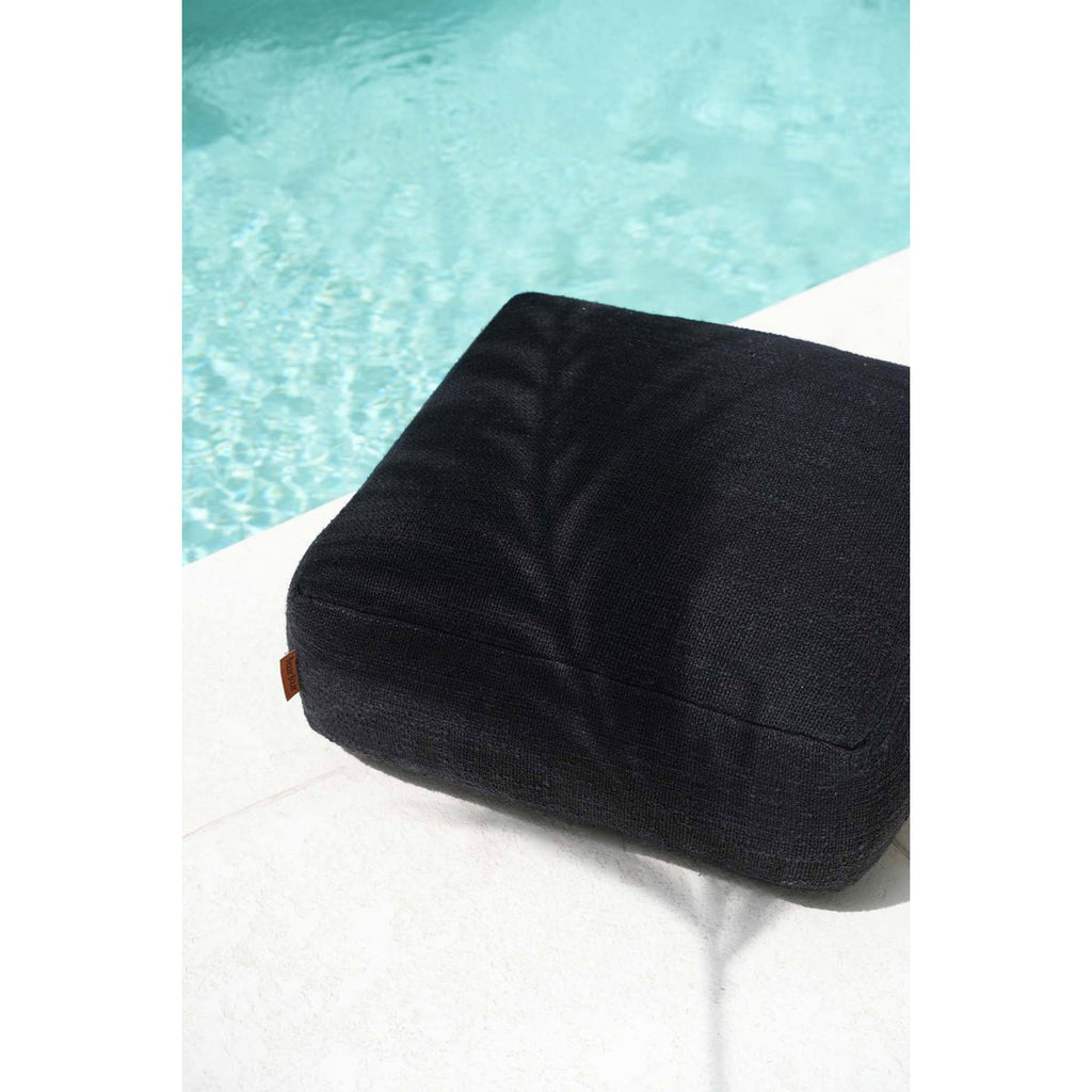 Mise en scène du pouf noir moelleux utilisé comme assise relaxante en extérieur au bord d'une piscine