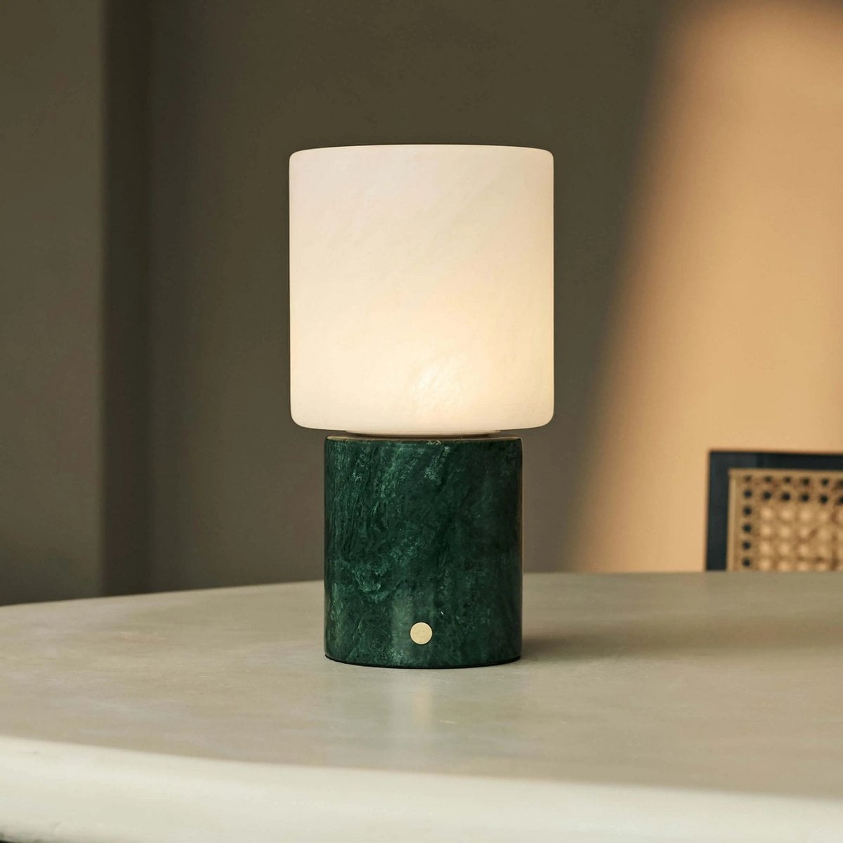 Lampe de table sans fil Cuyp en marbre vert allumée sur une table ronde.