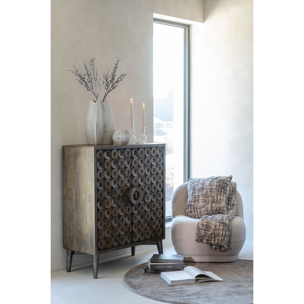 Décoration salon cosy avec coussin tweed marron posé sur un fauteuil près d'une fenêtre