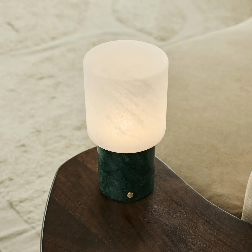 Lampe portable allumée posée sur un accoudoir de canapé en bois.