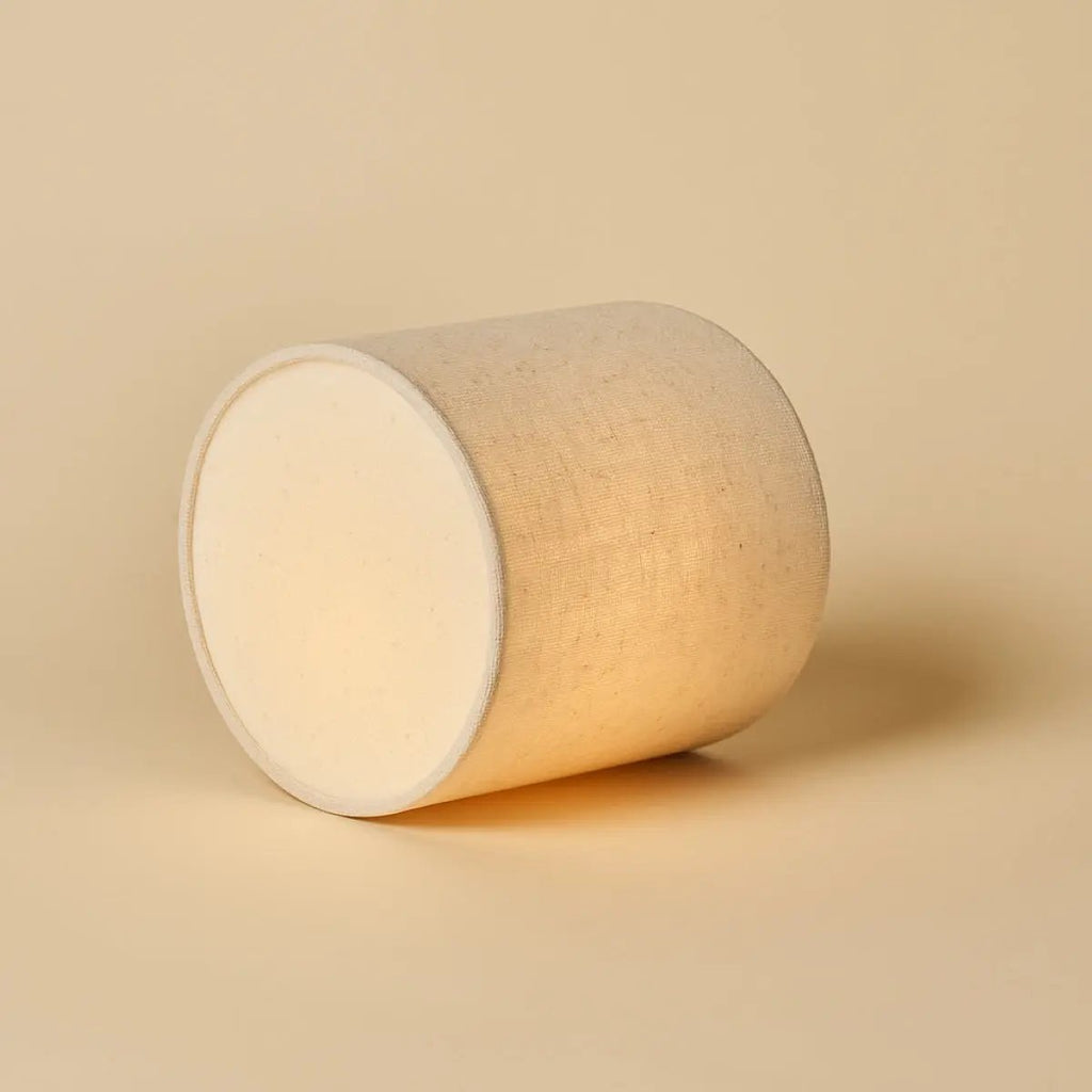 Vue de dessus de l'abat-jour en lin naturel allumé de la lampe Onoda.