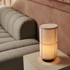 Lampe à poser Japandi diffusant une lumière douce, avec son abat-jour en lin texturé et son socle en bois.