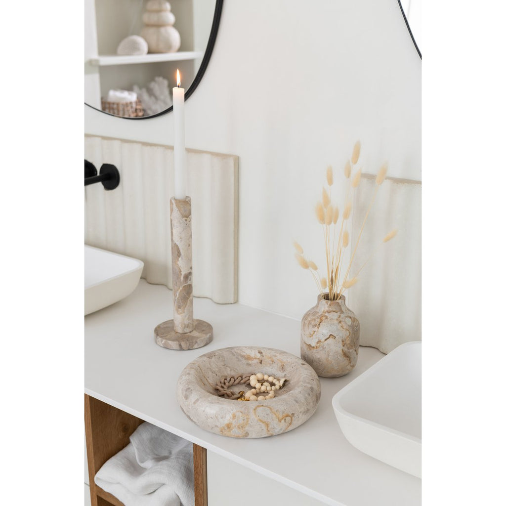 Mise en scène élégante des bougeoirs sur une commode lumineuse dans une salle de bain ou une chambre.