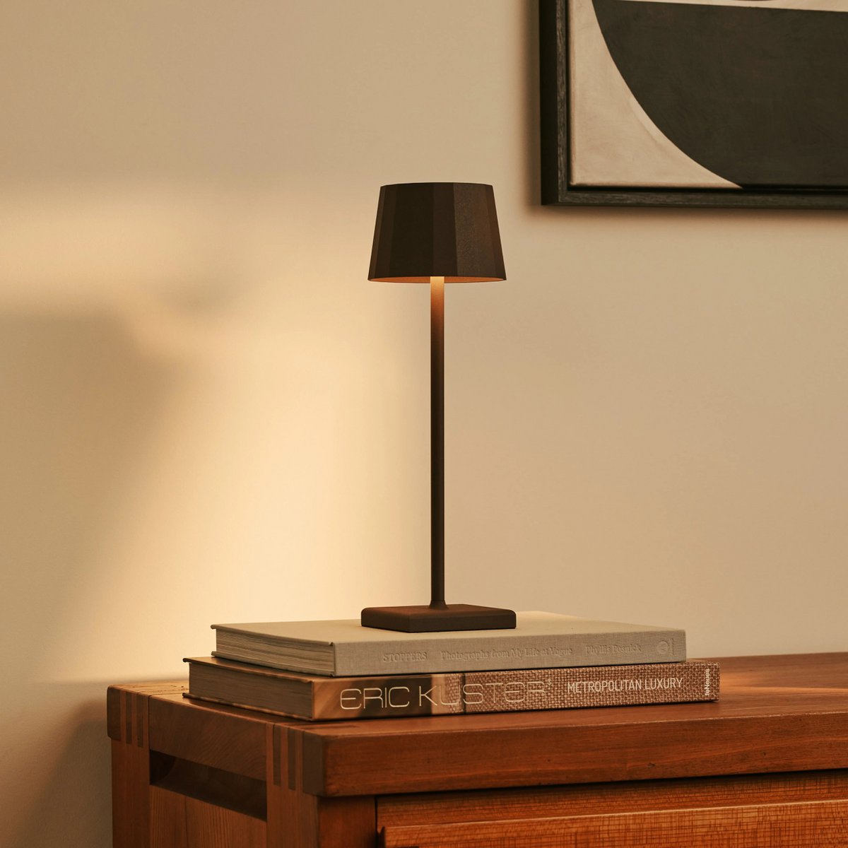Lampe de bureau sans fil design moka éclairant des livres d'art posés sur une console.