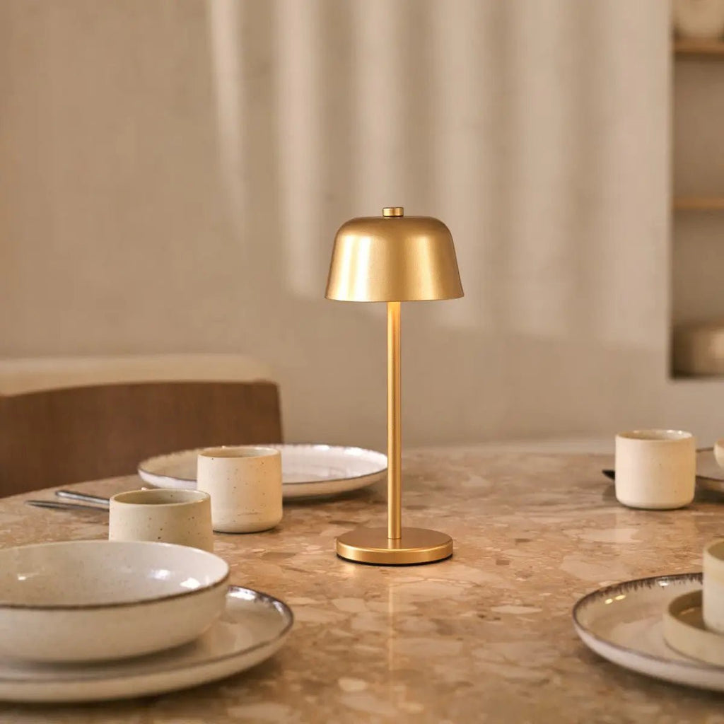 Dîner éclairé par la lampe de table rechargeable Anton Or ambiance restaurant chic.