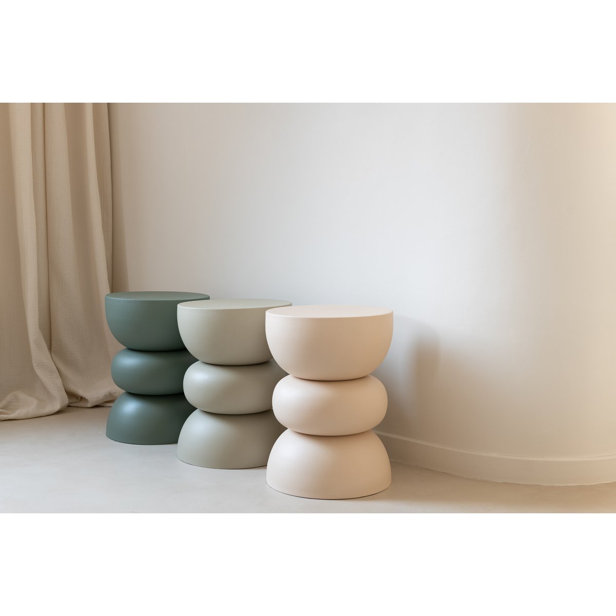 Mise en scène montrant plusieurs coloris de cette table d'appoint sculpturale dans un intérieur minimaliste.