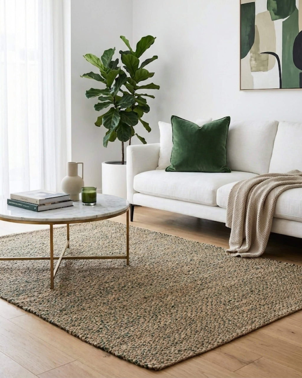 Tapis rectangulaire en jute et coton coloris vert fougère Elliot placé dans un salon moderne lumineux. Il est mis en valeur par un canapé blanc orné d'un coussin en velours vert et d'une grande plante d'intérieur, créant une décoration style jardin d'hiver chic.
