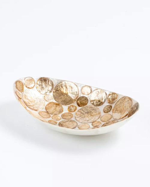 Une vue d'ensemble claire et nette de la coupelle ovale décorative façonnée à la main, posée sur un fond blanc pur. L'intérieur bicolore présente un motif complexe et lumineux de disques de nacre de Capiz naturelle (crème et doré) incrustés dans une résine blanche polie.