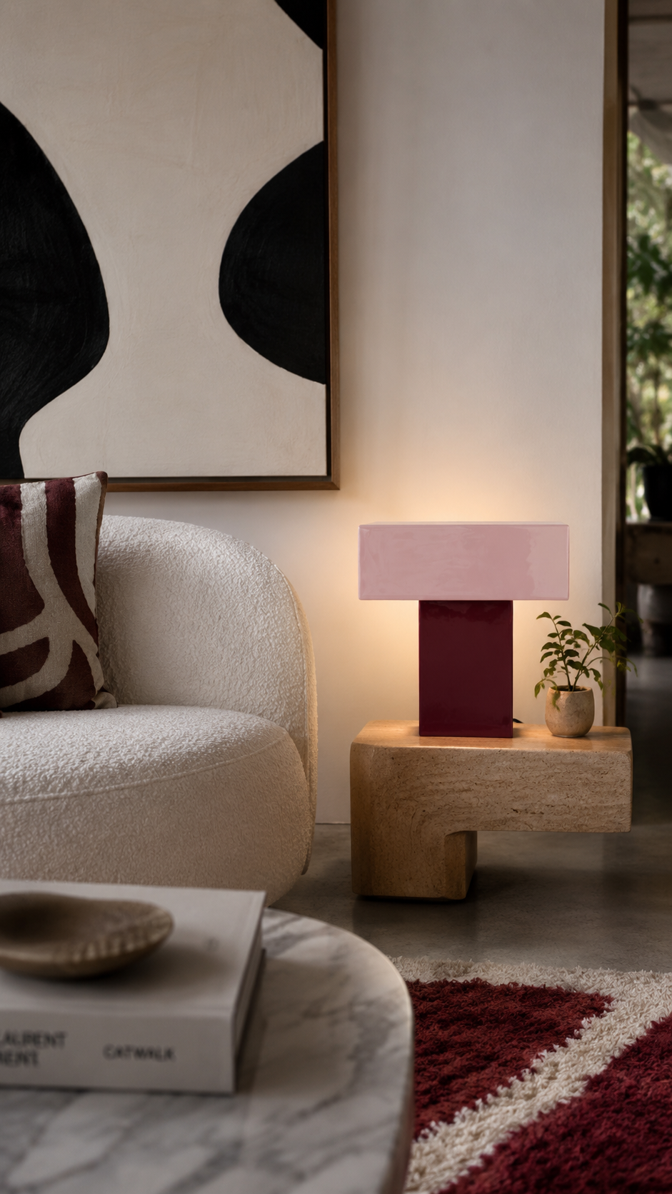 Lampe de table Grato Recto bordeaux allumée posée sur sellette en travertin dans salon canapé bouclette blanc tapis bordeaux tableau abstrait ambiance intérieure lumineuse