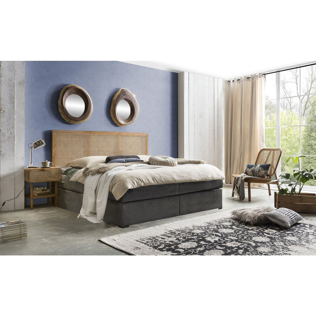 Mise en scène du fauteuil en teck et cannage dans un salon à l'ambiance chaleureuse et lumineuse.