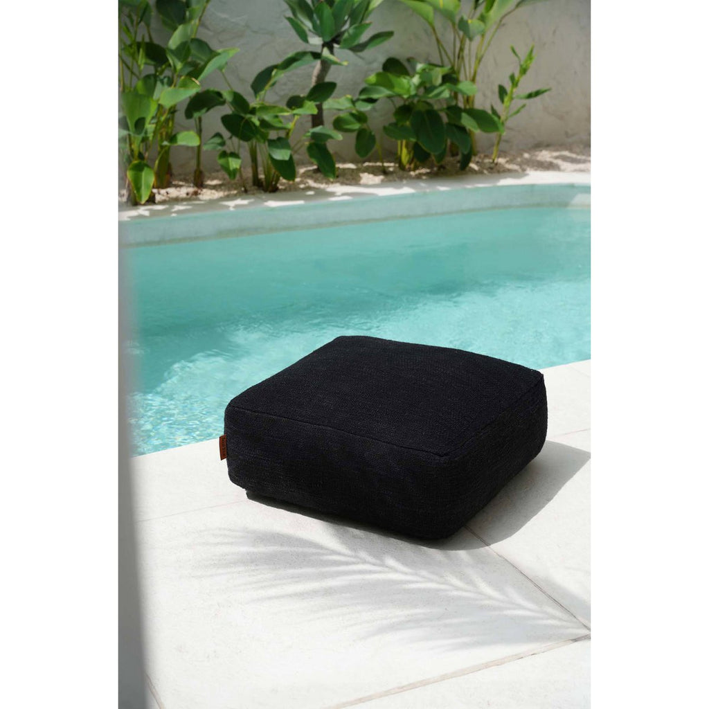 Mise en scène du pouf noir moelleux utilisé comme assise relaxante en extérieur.