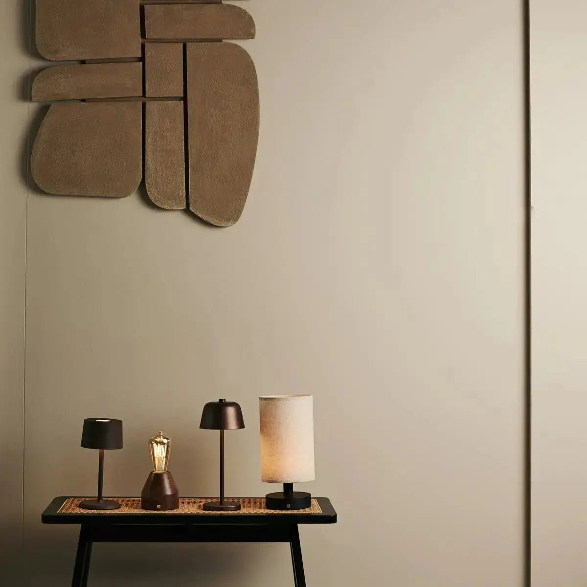 Lampe de table Anton marron posée sur un socle noir, ambiance galerie d'art.