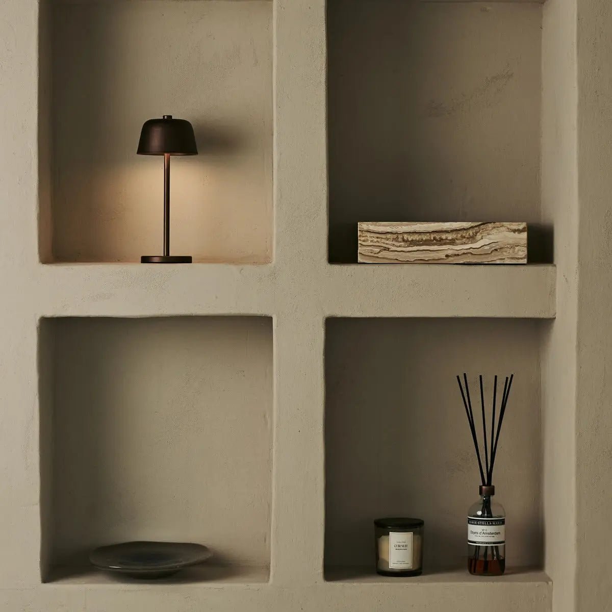 Lampe minimaliste marron Anton mise en valeur dans une étagère murale carrée.