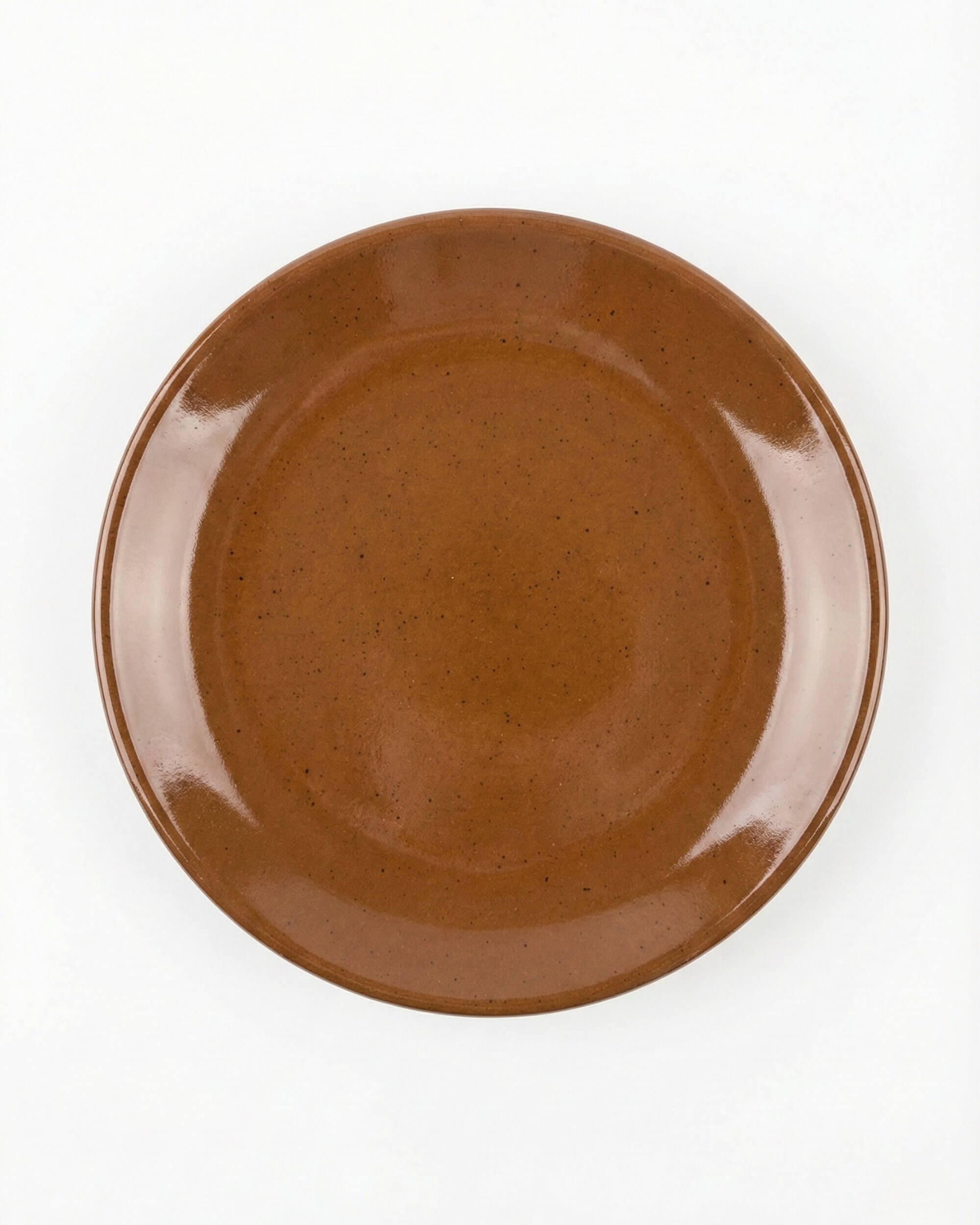 Détail de l'assiette Ambra montrant les reflets de l'émail artisanal couleur terre brûlée.