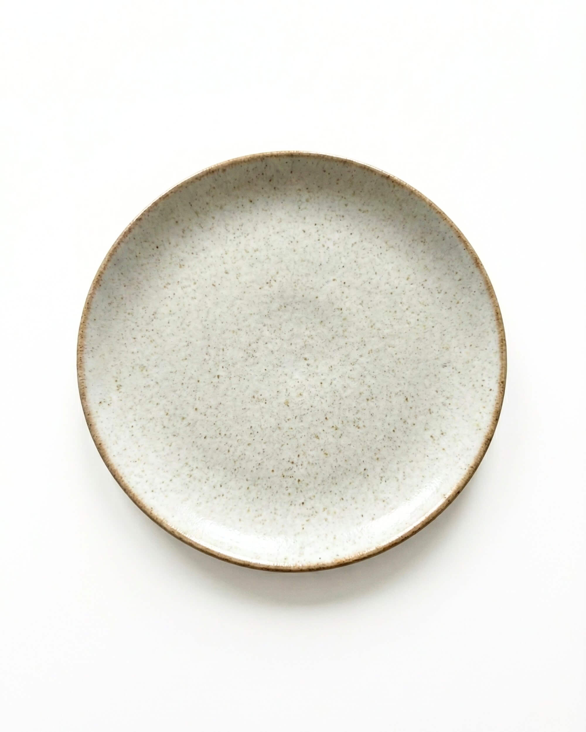 Vue de dessus de l'assiette Sienne en grès moucheté. Design épuré beige crème et forme ronde organique.