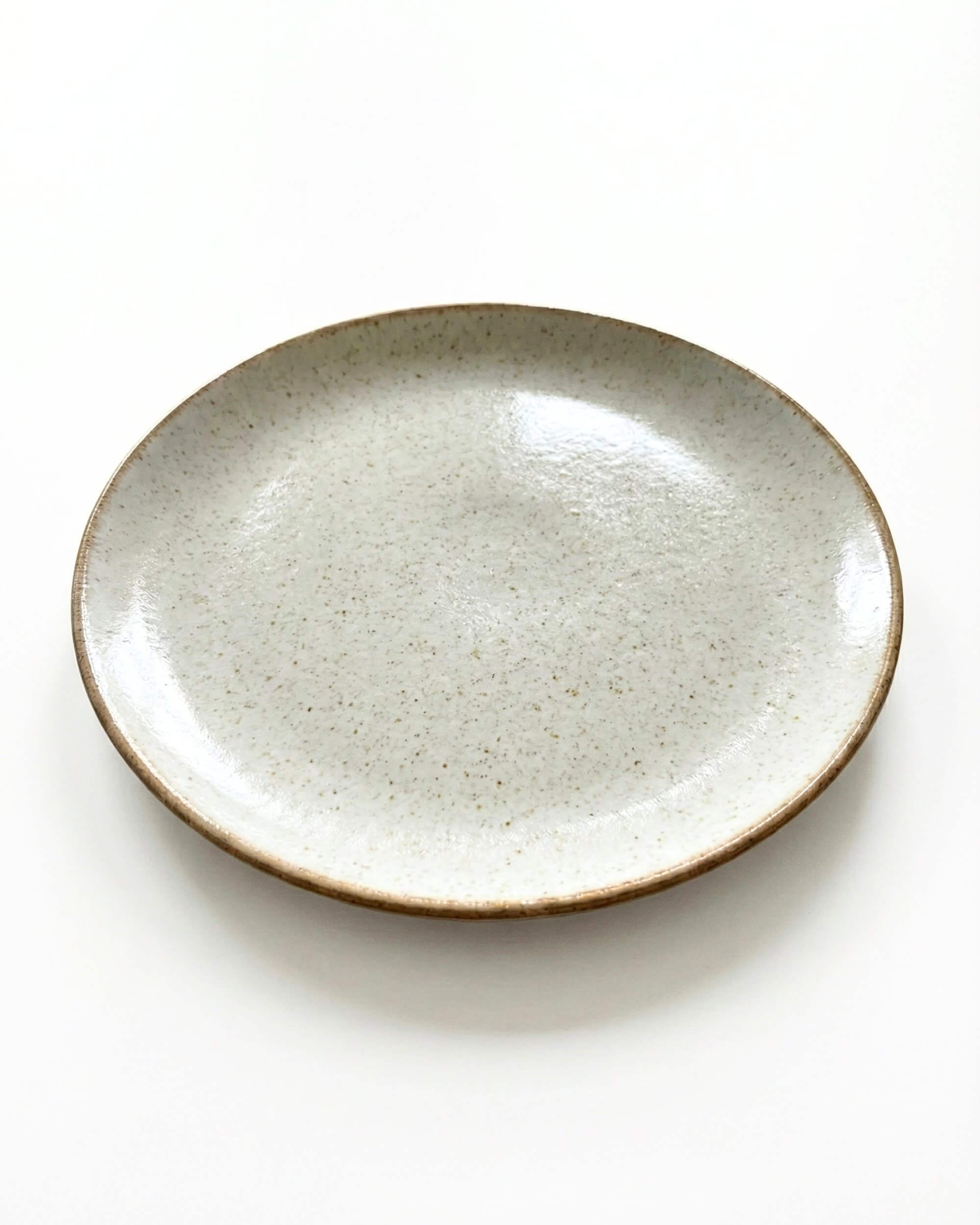 Vue détaillée de l'assiette Sienne montrant la texture irrégulière de l'émail et les bords légèrement relevés.