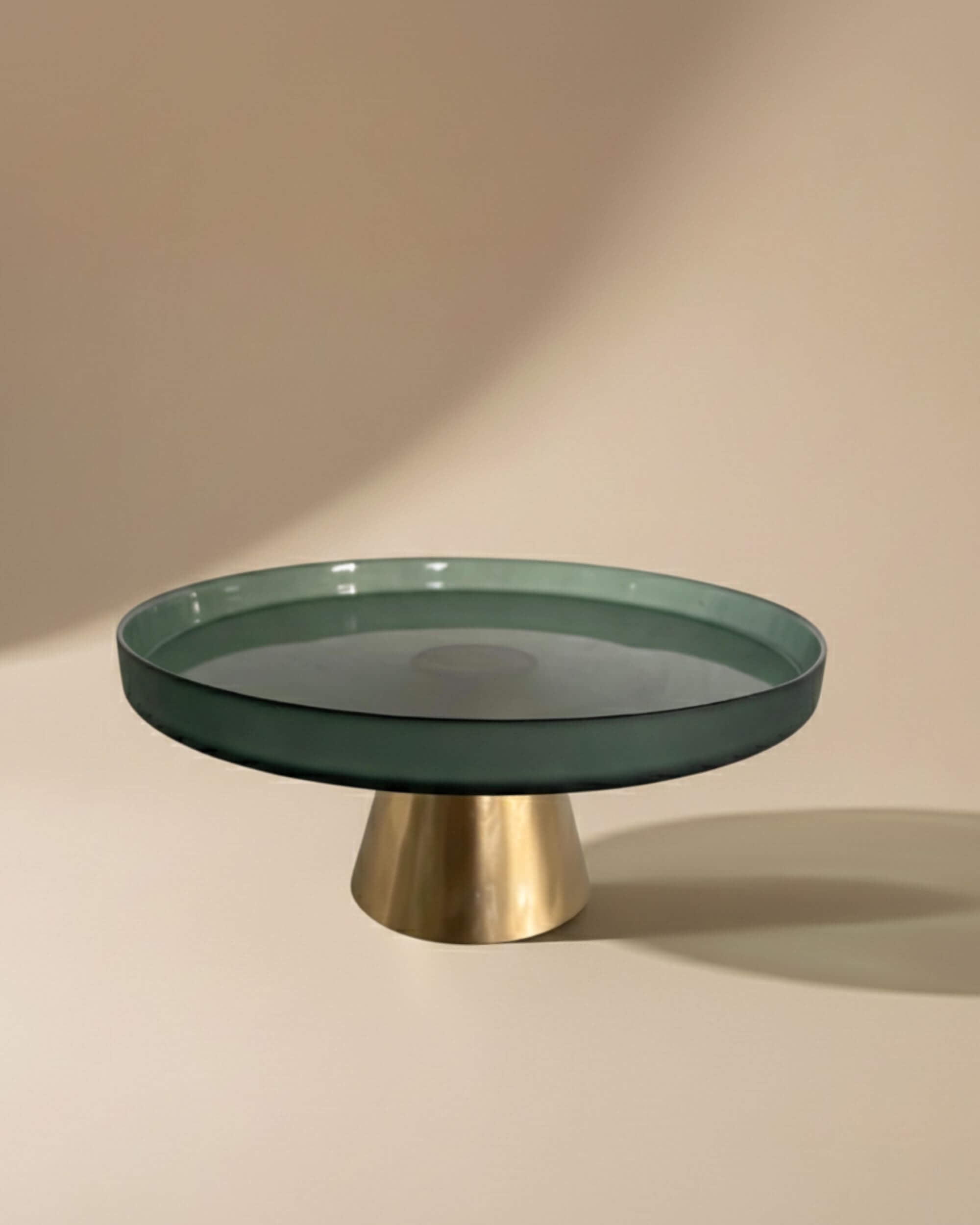 Plat à gâteau AYA en verre vert et doré éclairé par la lumière
