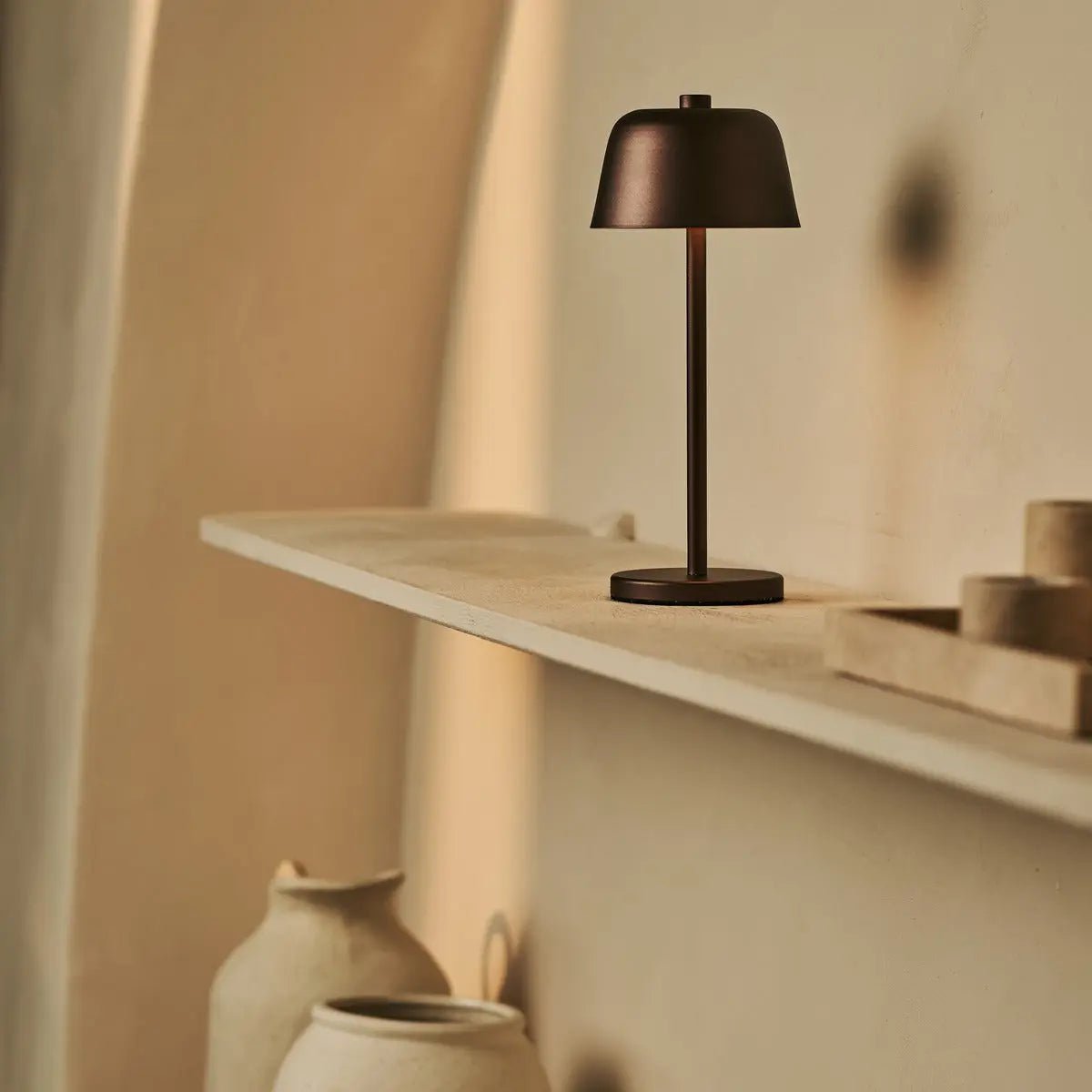 Lampe rechargeable Anton Espresso sur une longue étagère murale épurée.