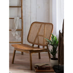 Mise en scène du fauteuil en teck et cannage dans un salon à l'ambiance chaleureuse et lumineuse.