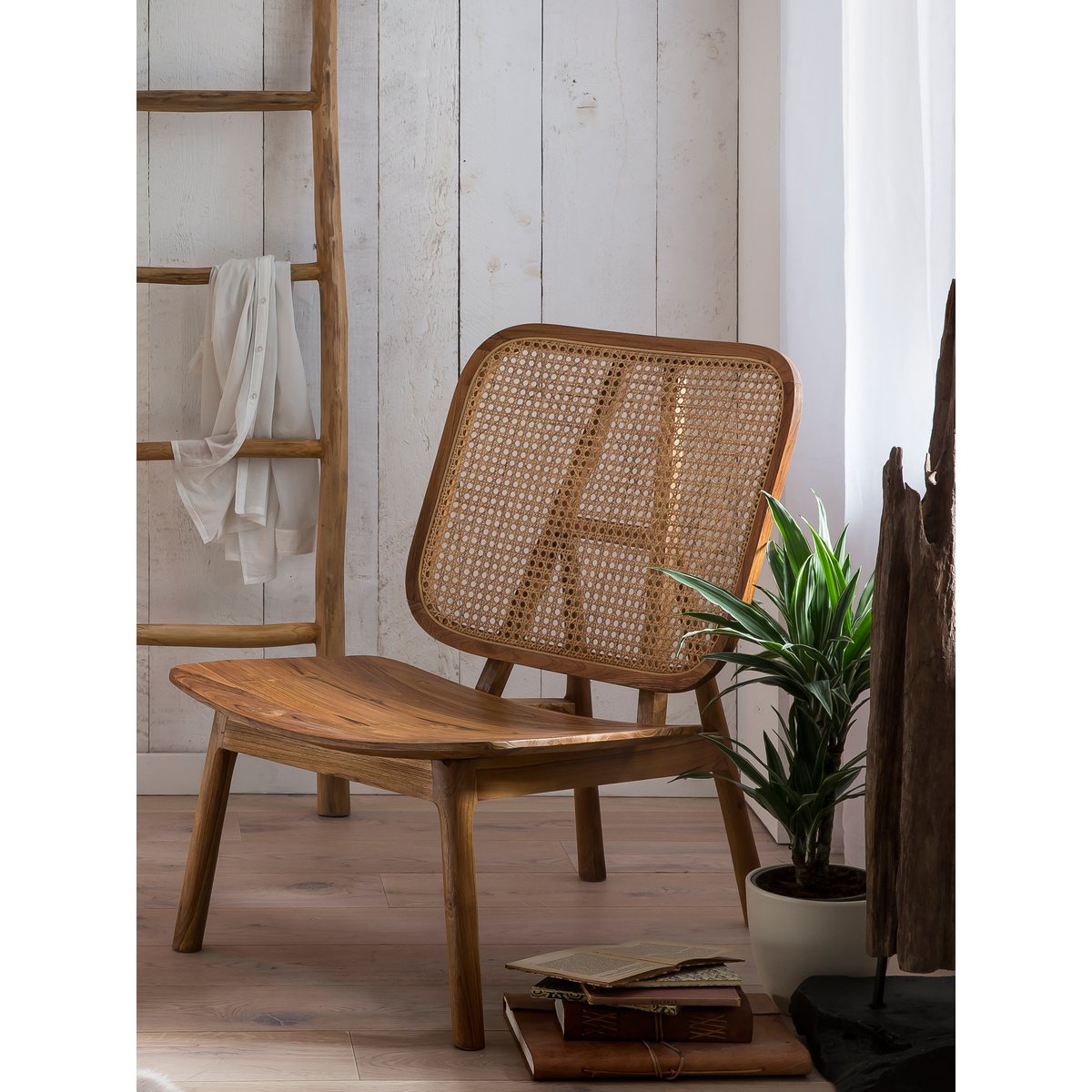 Mise en scène du fauteuil en teck et cannage dans un salon à l'ambiance chaleureuse et lumineuse.