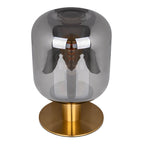 Lampe de table design Alessio, base cylindrique en métal doré et grand abat-jour en verre fumé translucide.
