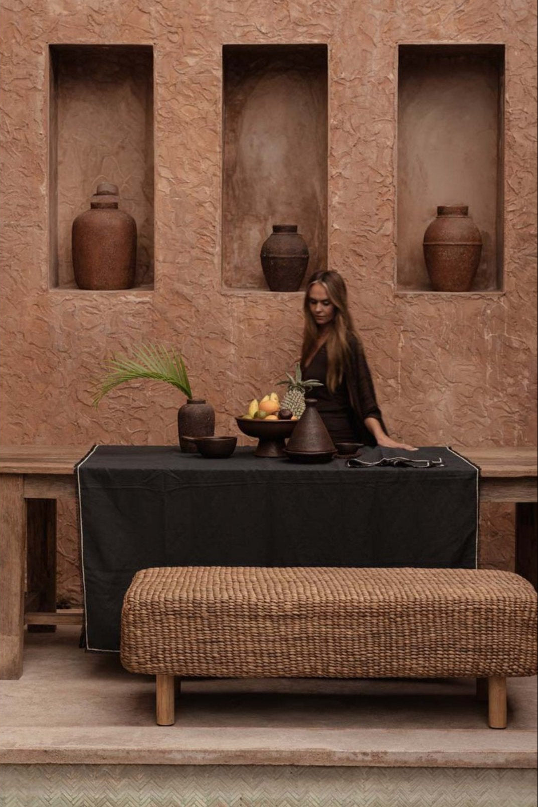 Mise en scène chaleureuse du banc tressé dans un salon aux tons neutres et organiques.