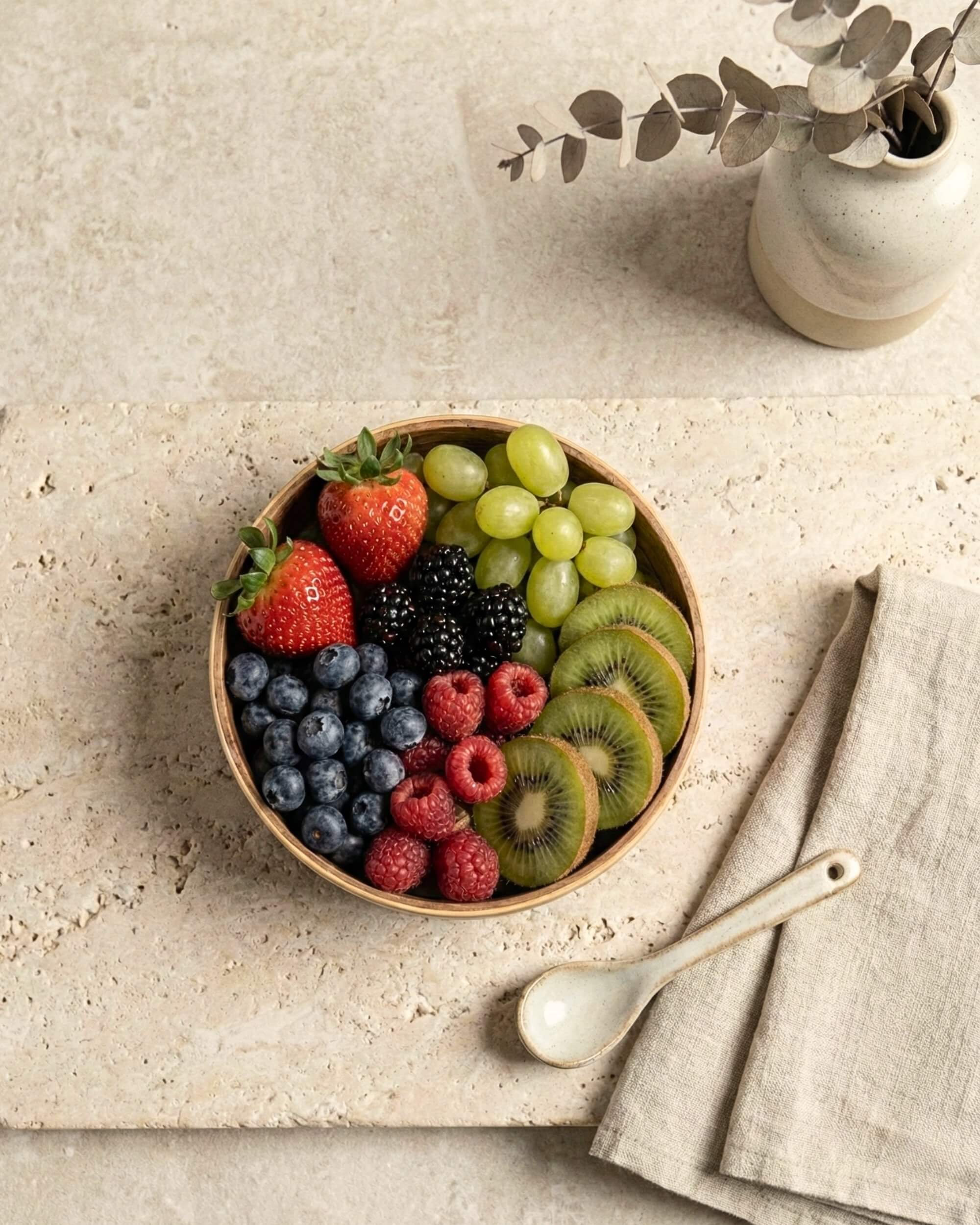 Vue de dessus du bol en bois Soraya rempli de fruits frais. Idéal pour les petits-déjeuners sains ou les apéritifs.