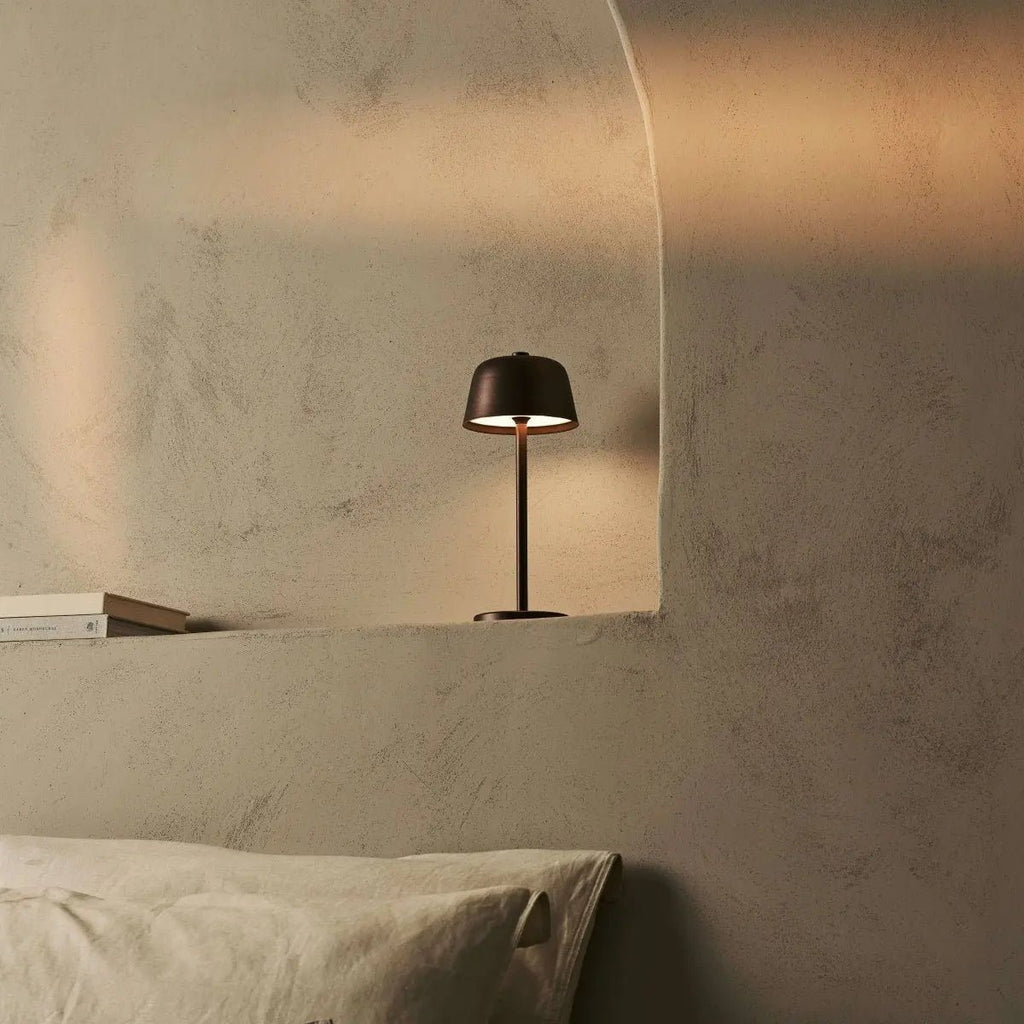 Lampe design bronze Anton posée dans une niche décorative en forme d'arche.