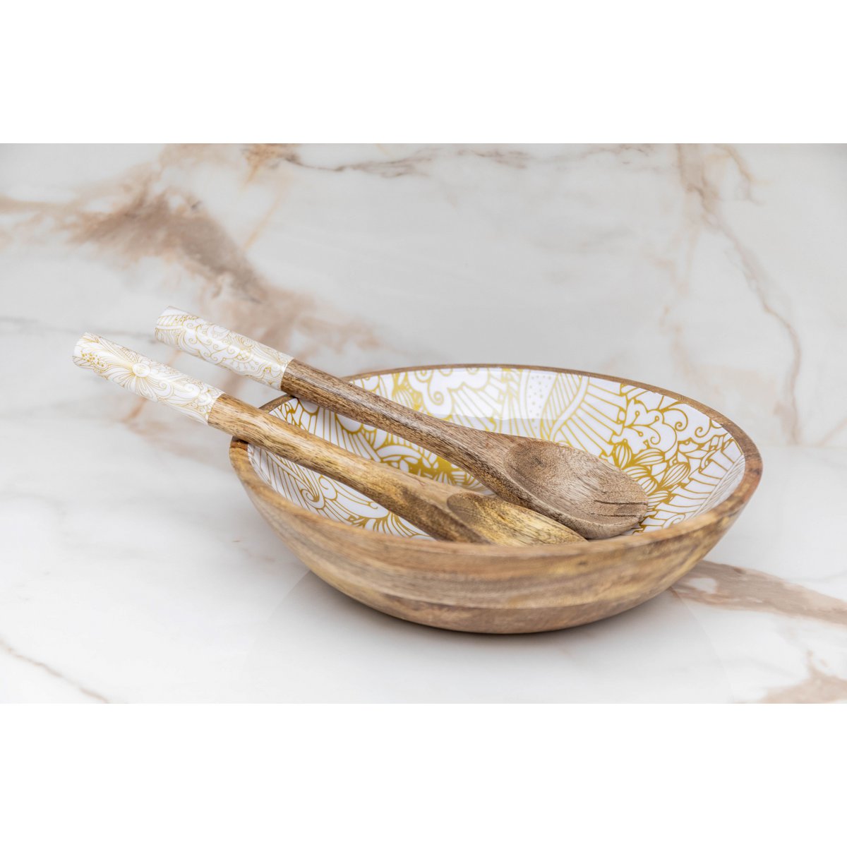 Mise en scène élégante des couverts à salade en bois posés dans une jolie coupelle dorée.