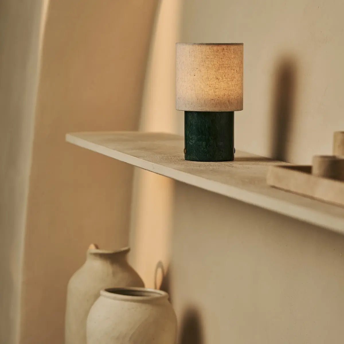 Lampe sans fil en marbre vert Onoda sur une étagère en bois minimaliste.