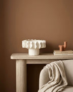 Vue de face de la coupe sur pied Hélios en céramique blanche mate avec bords ondulés design.