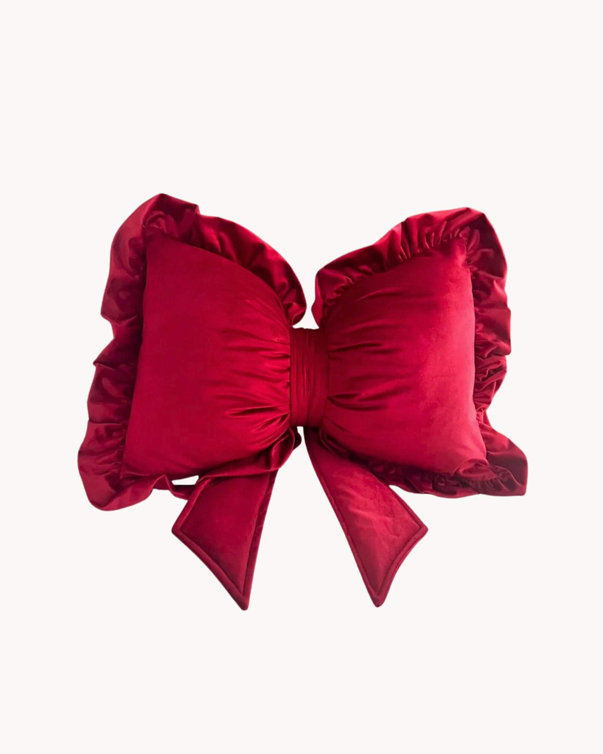 Coussin CARMINE en velours rouge profond, en forme de grand nœud avec bord volanté, sur fond blanc.