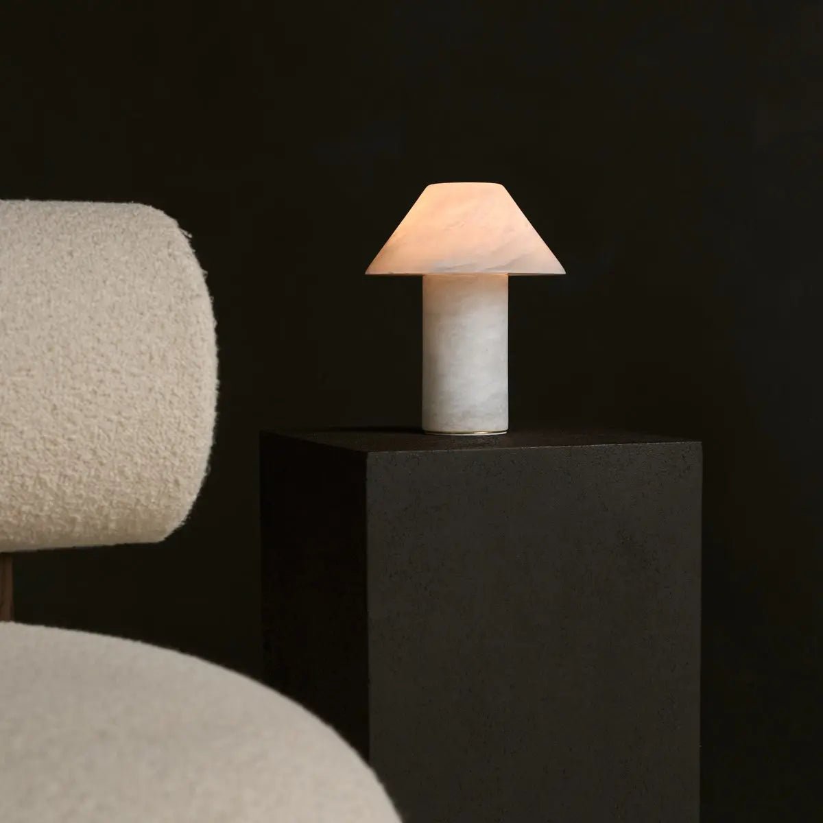 Lampe sculpturale en albâtre blanc éteinte sur fond noir.