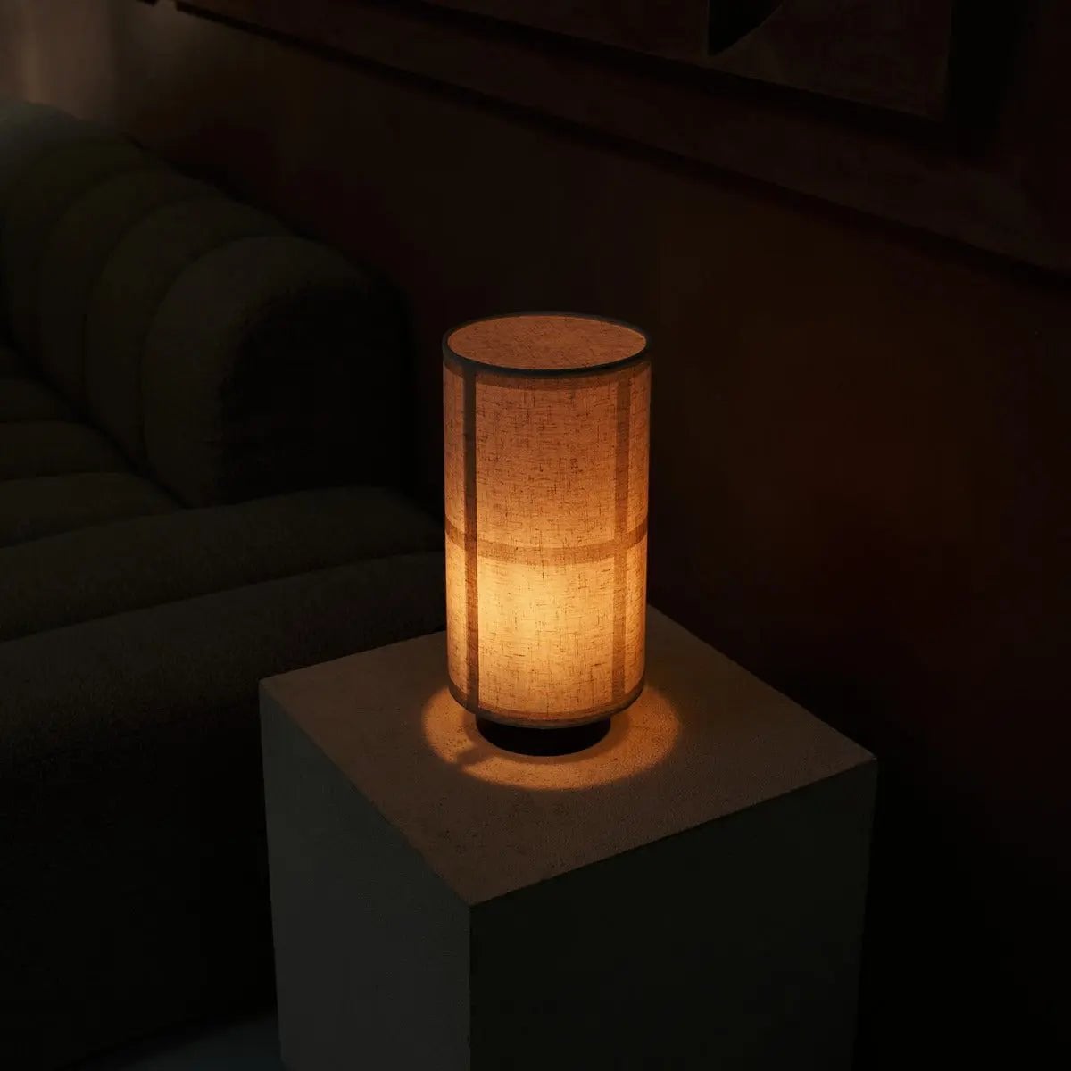 La lampe allumée dans la pénombre, soulignant le subtil quadrillage de l'abat-jour d'inspiration japonaise.