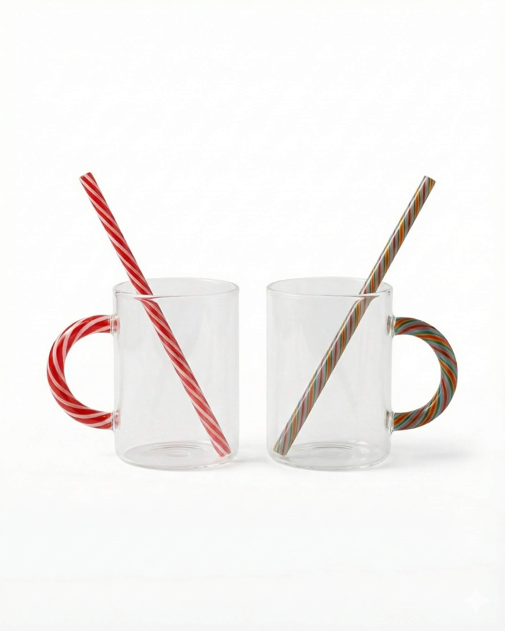 Vue de face des mugs Candy Cane sur fond blanc. Détail des anses colorées rouge et multicolore style sucre d'orge avec pailles en verre incluses.