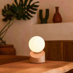 Lampe à poser nomade et sans fil, avec son globe en verre dépoli lumineux et son élégant socle en bois clair.