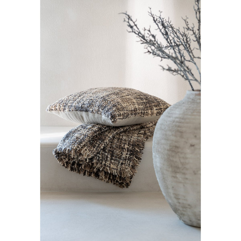 Décoration naturelle wabi-sabi avec coussin tweed marron Highland empilé sur un plaid assorti près d'un vase en pierre