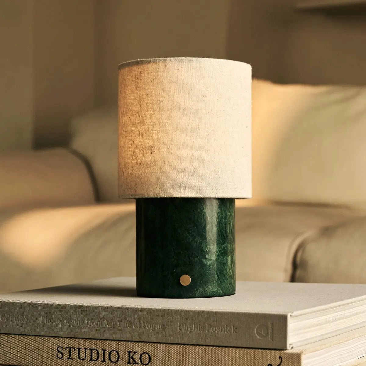 Lampe nomade Onoda posée sur des livres de design, ambiance salon chaleureux.