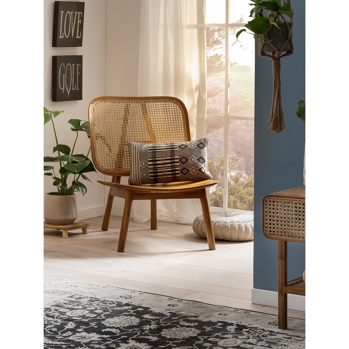 Mise en scène du fauteuil en teck et cannage dans un salon à l'ambiance chaleureuse et lumineuse.